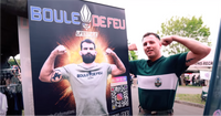 Romain Debienne, combattant pro de MMA, pose fièrement devant l'affiche du stand Boule de Feu, mettant en avant Benoît Saint Denis, combattant UFC, portant un t-shirt Boule de Feu à la 13ème DBLE de la Légion Étrangère.