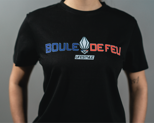 Vue rapprochée du t-shirt Frenchy Boule de Feu noir en coton biologique avec logo bleu blanc rouge porté par une femme